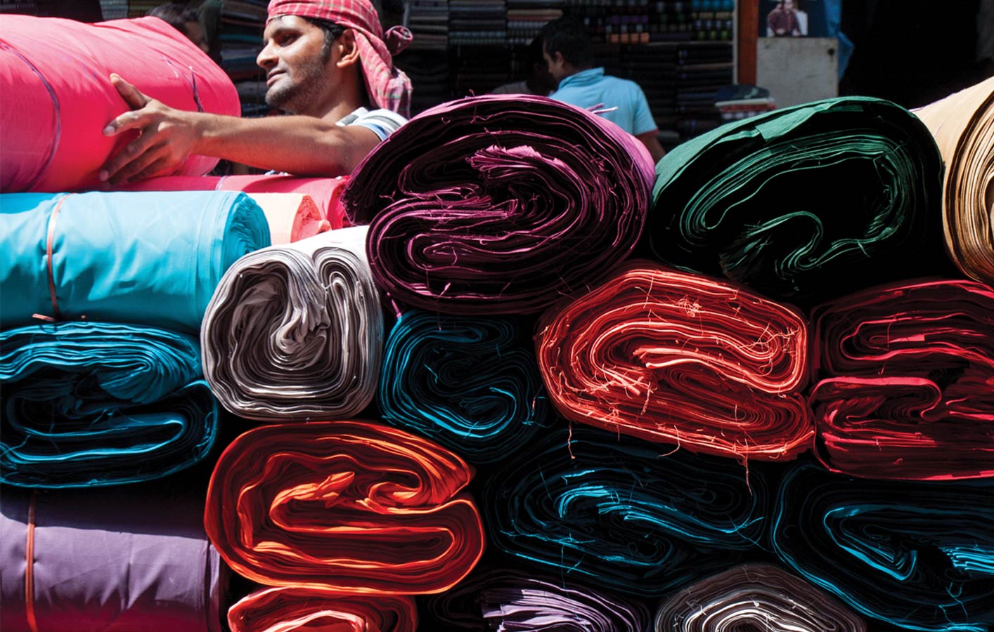 <p>Bolts of fabric for sale in Old Dhaka. A sari starts with nine meters of seamless fabric saturated with color.</p>